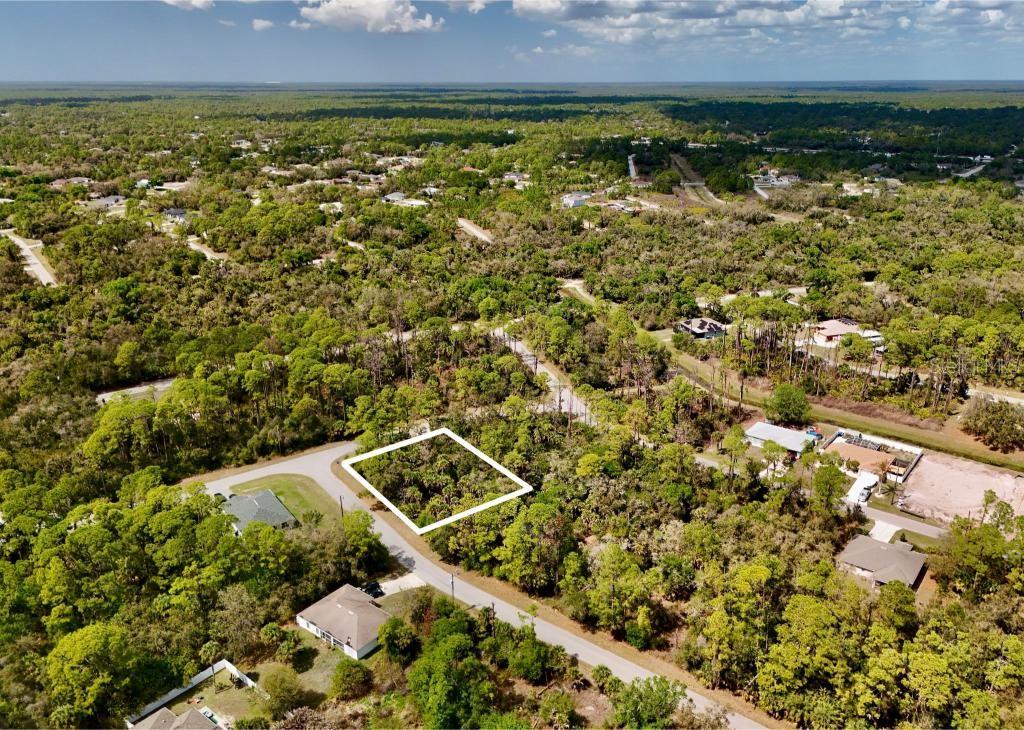An aerial view shows a vacant, wooded residential lot outlined in white along a paved road — LANDRY AVENUE, NORTH PORT, FL