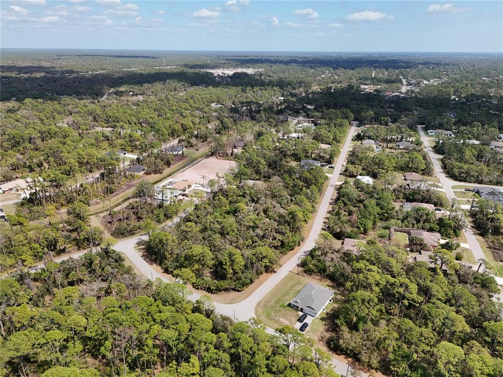 An aerial view shows a residential neighborhood with scattered houses surrounded by dense forest — LANDRY AVENUE, NORTH PORT, FL