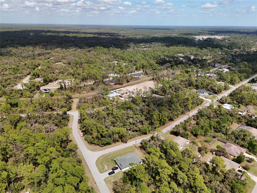 An aerial view shows a residential neighborhood with scattered houses surrounded by dense forest — LANDRY AVENUE, NORTH PORT, FL