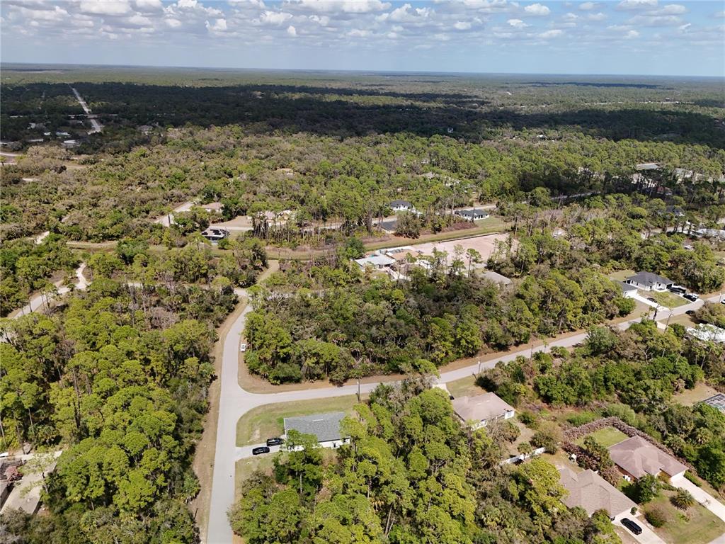 An aerial view shows a residential neighborhood with scattered houses surrounded by dense forest — LANDRY AVENUE, NORTH PORT, FL