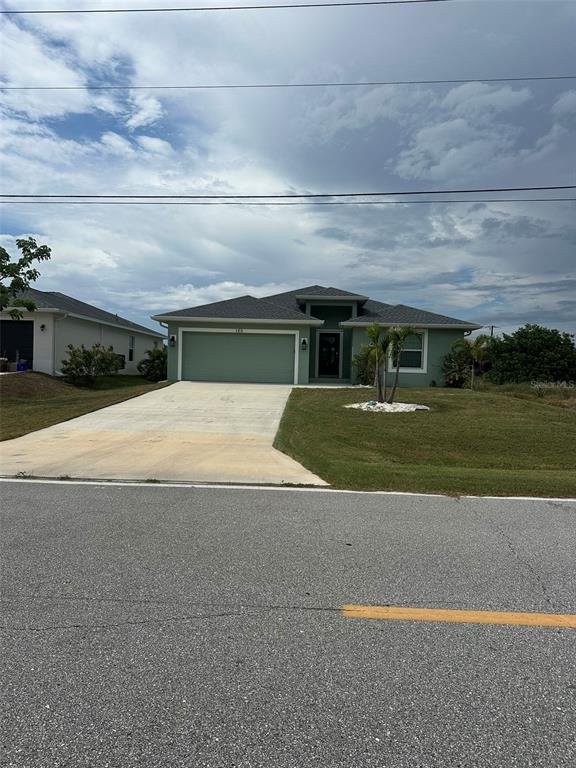 A single-story house with a green exterior, a two-car garage, and a concrete driveway — 160 SUNSET ROAD, ROTONDA WEST, FL