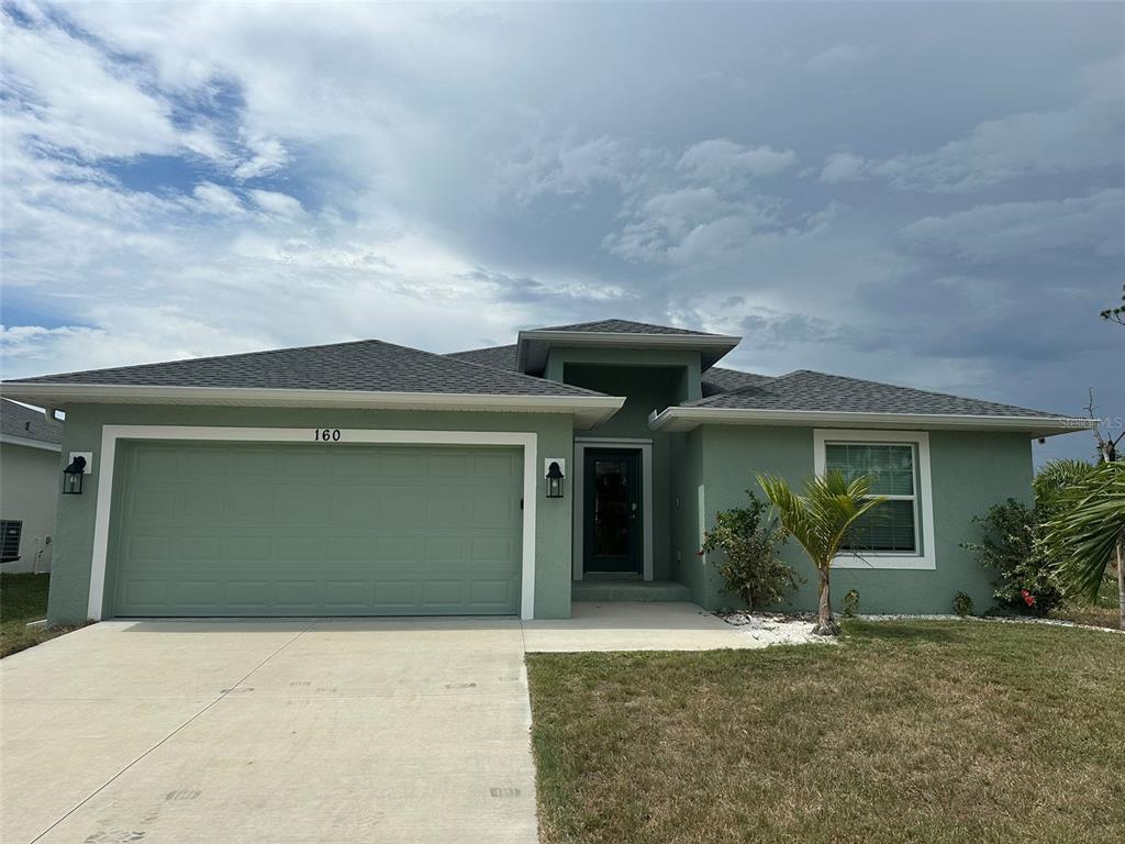 A single-story house with a green exterior, a two-car garage, and a front entryway — 160 SUNSET ROAD, ROTONDA WEST, FL