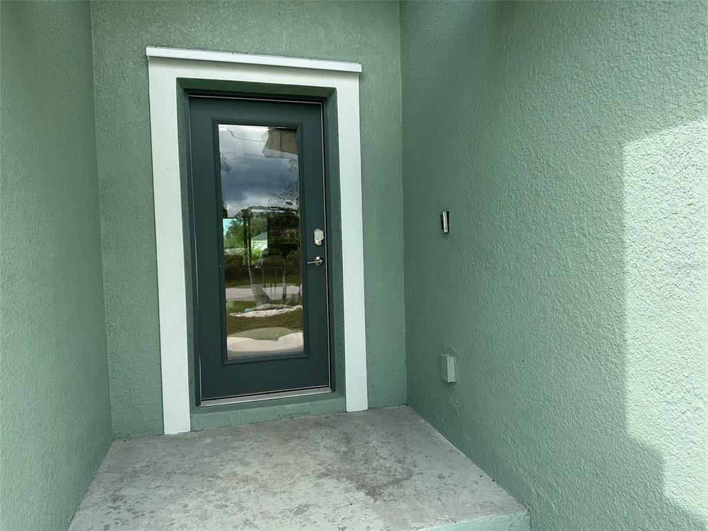 A dark-framed glass door with white trim is set into a light green stucco wall — 160 SUNSET ROAD, ROTONDA WEST, FL