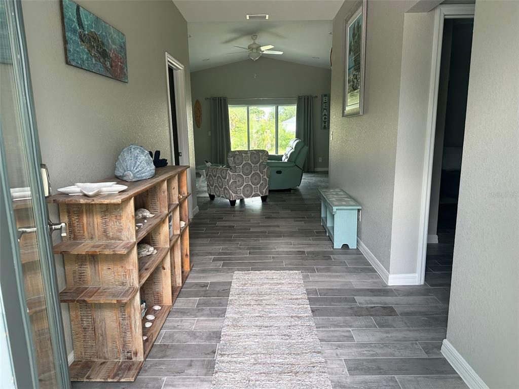 A view from an entryway looking down a hallway toward a living room with tile floors — 160 SUNSET ROAD, ROTONDA WEST, FL