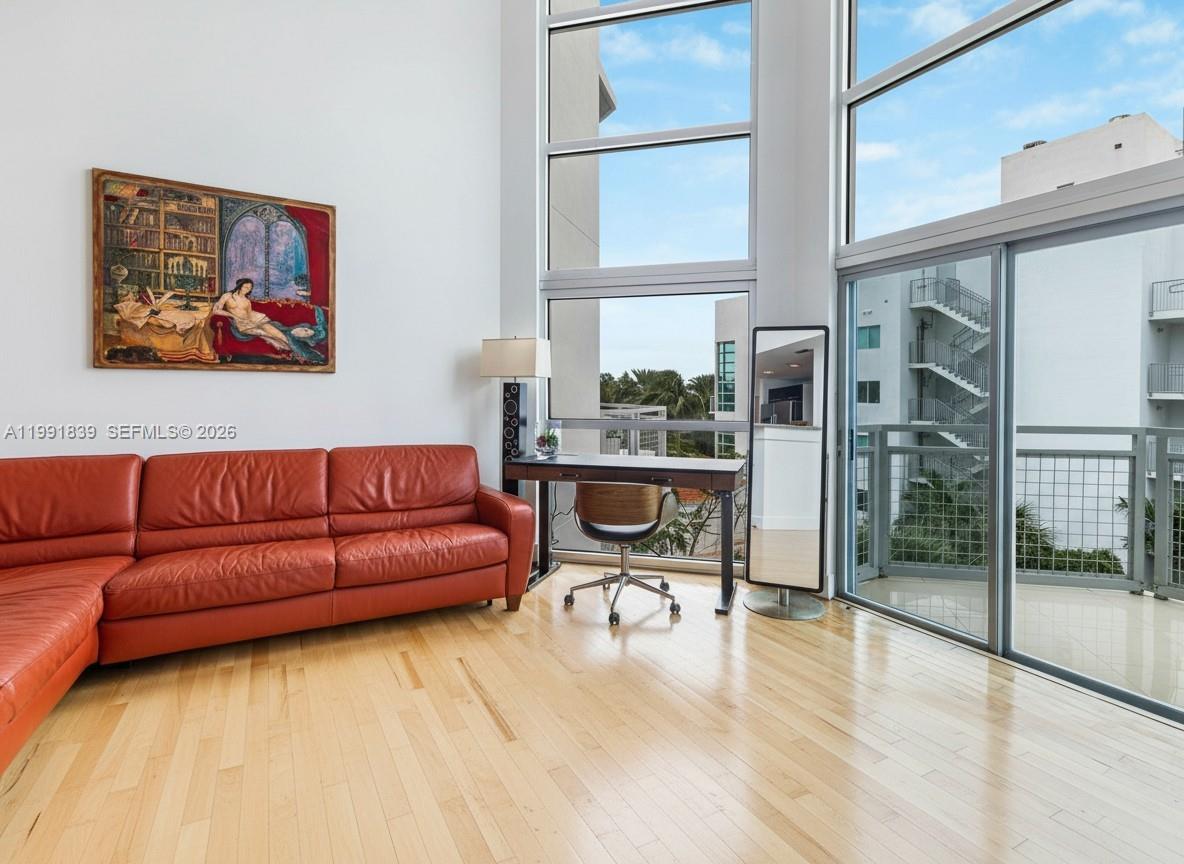 A living room features a red leather sofa, a desk, and floor-to-ceiling windows — 7728 Collins Ave # 16, Miami Beach FL 33141, MIAMI BEACH, FL