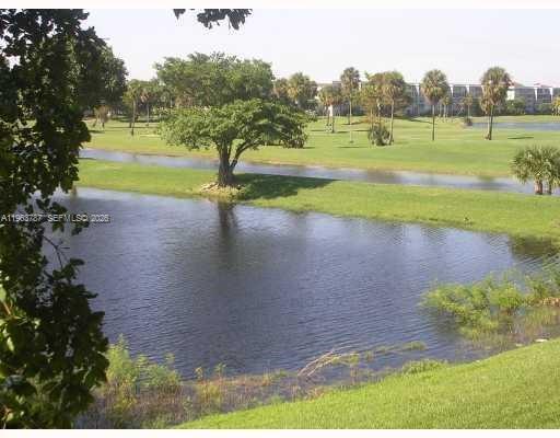 A view of a pond and a golf course with palm trees and a building — 4055 W Mcnab Rd # H303, Pompano Beach FL 33069, POMPANO BEACH, FL
