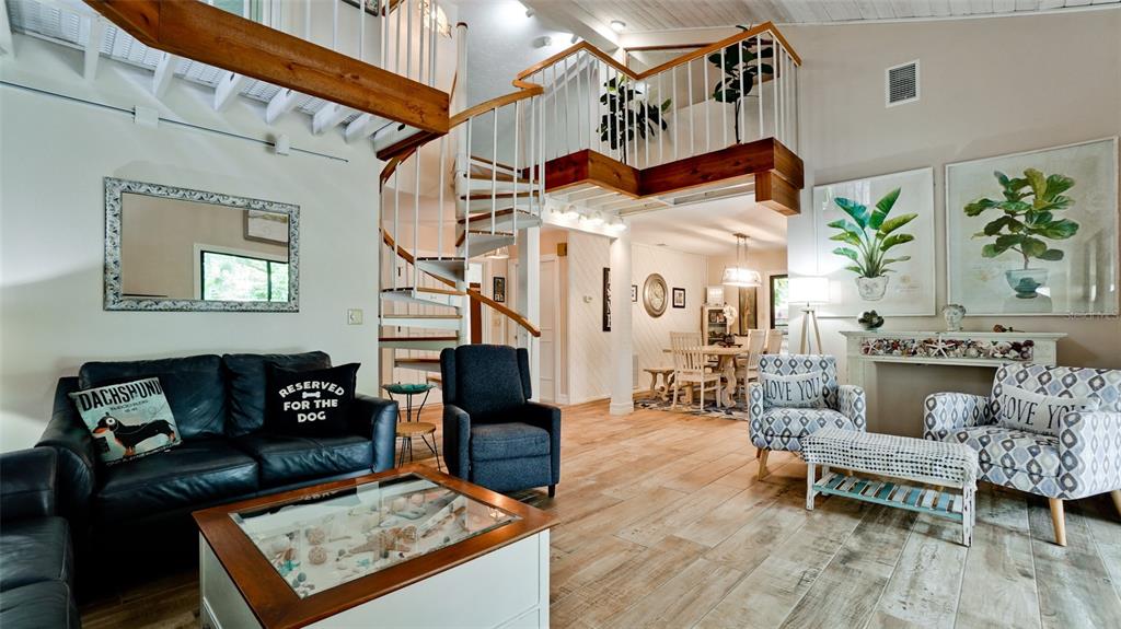 A living room features a spiral staircase, wood-look tile flooring, and a glass-topped coffee table — 2407 QUAIL COURT, BRADENTON, FL