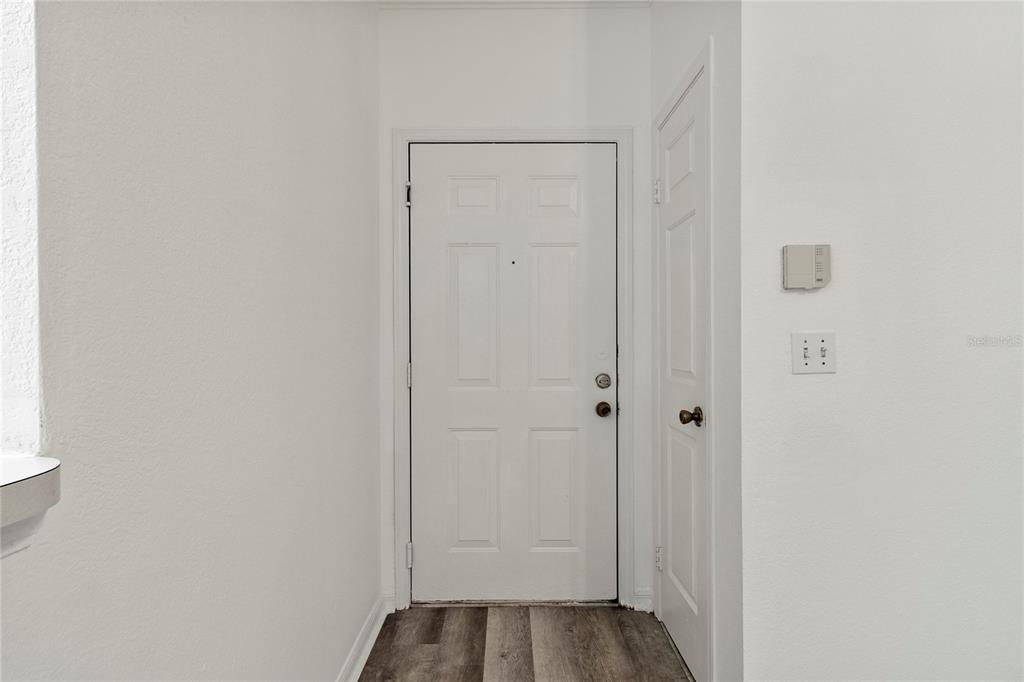An interior entryway features a white front door, a side closet door, and wood-look flooring — 2648 ROBERT TRENT JONES DRIVE UNIT 223, ORLANDO, FL