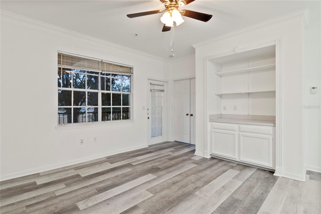 A room with wood-look flooring, a ceiling fan, a window, a door, and built-in shelving — 2648 ROBERT TRENT JONES DRIVE UNIT 223, ORLANDO, FL