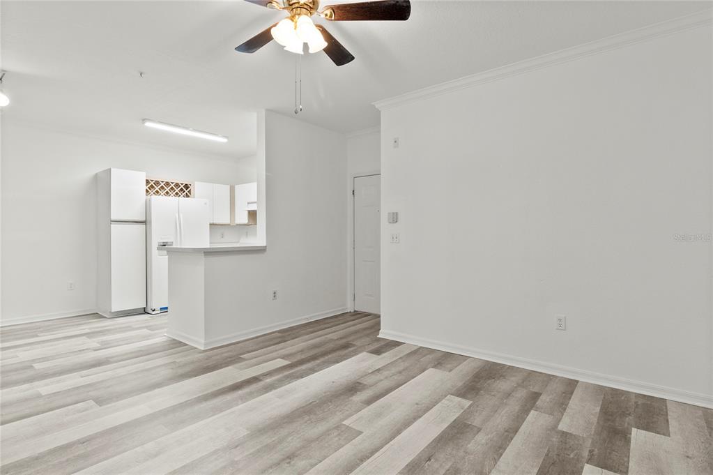 An open-concept living area features light wood-look flooring, white walls, and an adjacent kitchen — 2648 ROBERT TRENT JONES DRIVE UNIT 223, ORLANDO, FL