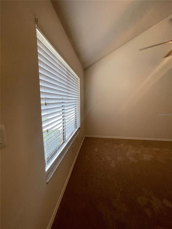 A room with beige carpet, a vaulted ceiling, and a window covered by white blinds — 3504 NW 37TH AVENUE, GAINESVILLE, FL