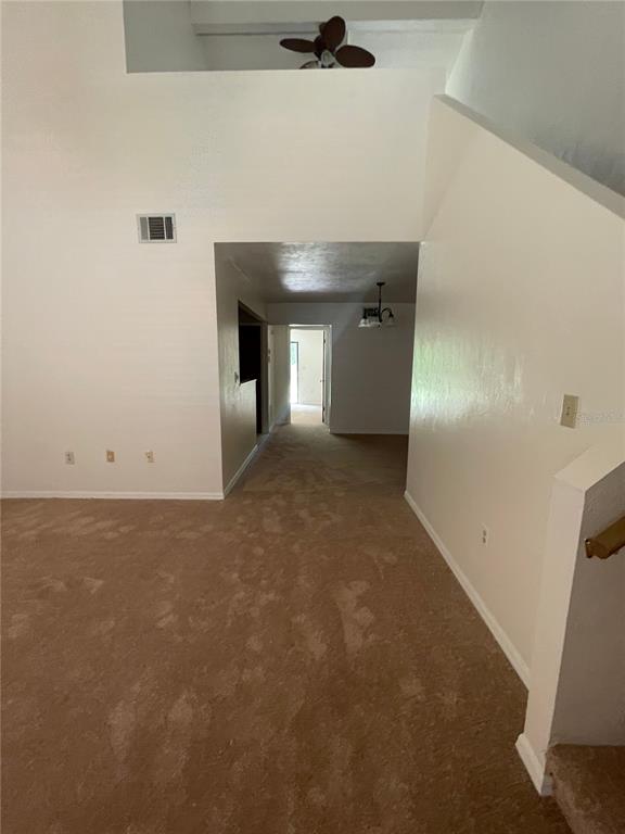 A carpeted living room with a vaulted ceiling, a ceiling fan, and a hallway entrance — 3504 NW 37TH AVENUE, GAINESVILLE, FL