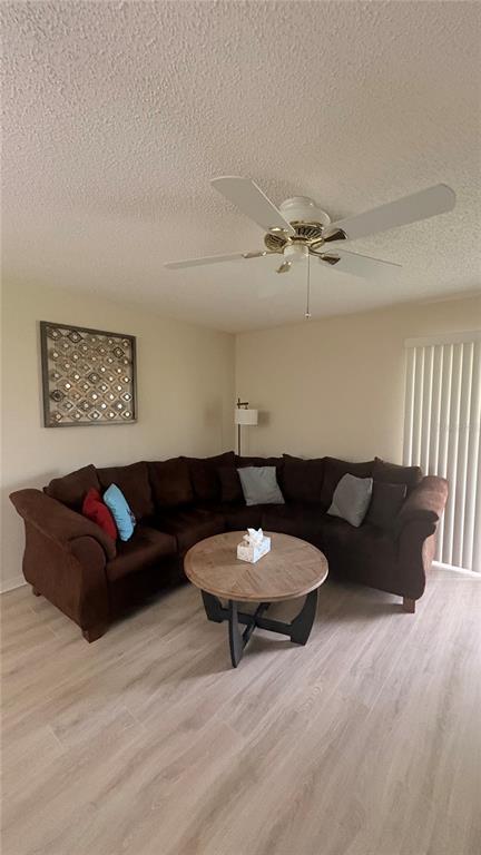A living room features a brown sectional sofa, a round wooden coffee table, and a ceiling fan — 773 ARTESIA AVENUE, THE VILLAGES, FL