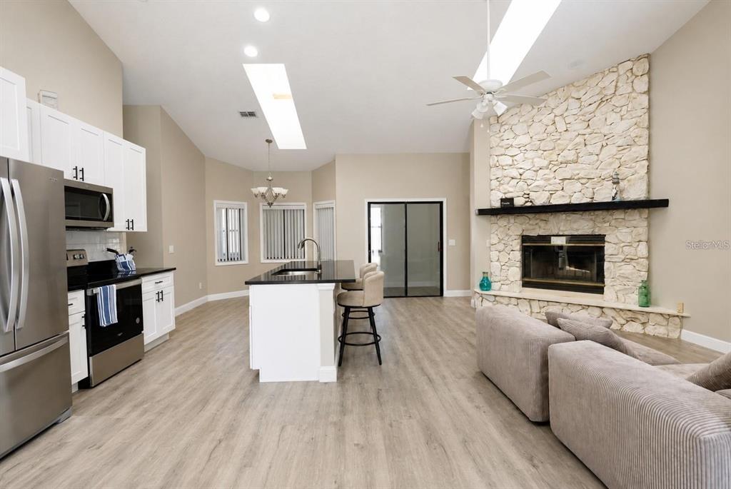 A kitchen and living area featuring a stone fireplace, white cabinets, and a kitchen island — 10 FALLS PLACE, PALM COAST, FL