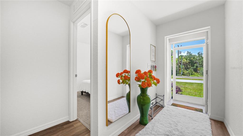 An entryway features a tall arched mirror, a green vase with flowers, and a door — 4236 GARBETT TERRACE, NORTH PORT, FL