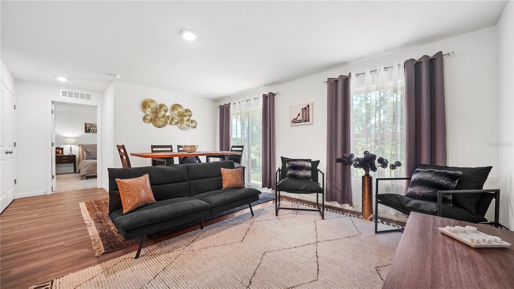 A living room features a black sofa, two armchairs, a dining area, and wood-look flooring — 4236 GARBETT TERRACE, NORTH PORT, FL
