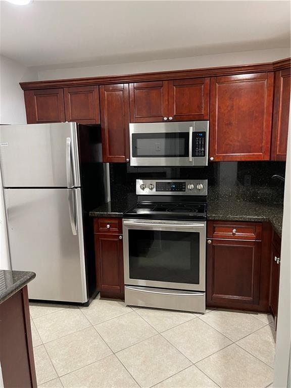 A kitchen features stainless steel appliances, dark wood cabinetry, and granite countertops — 6549 Somerset Drive # 106, Boca Raton FL 33433, BOCA RATON, FL