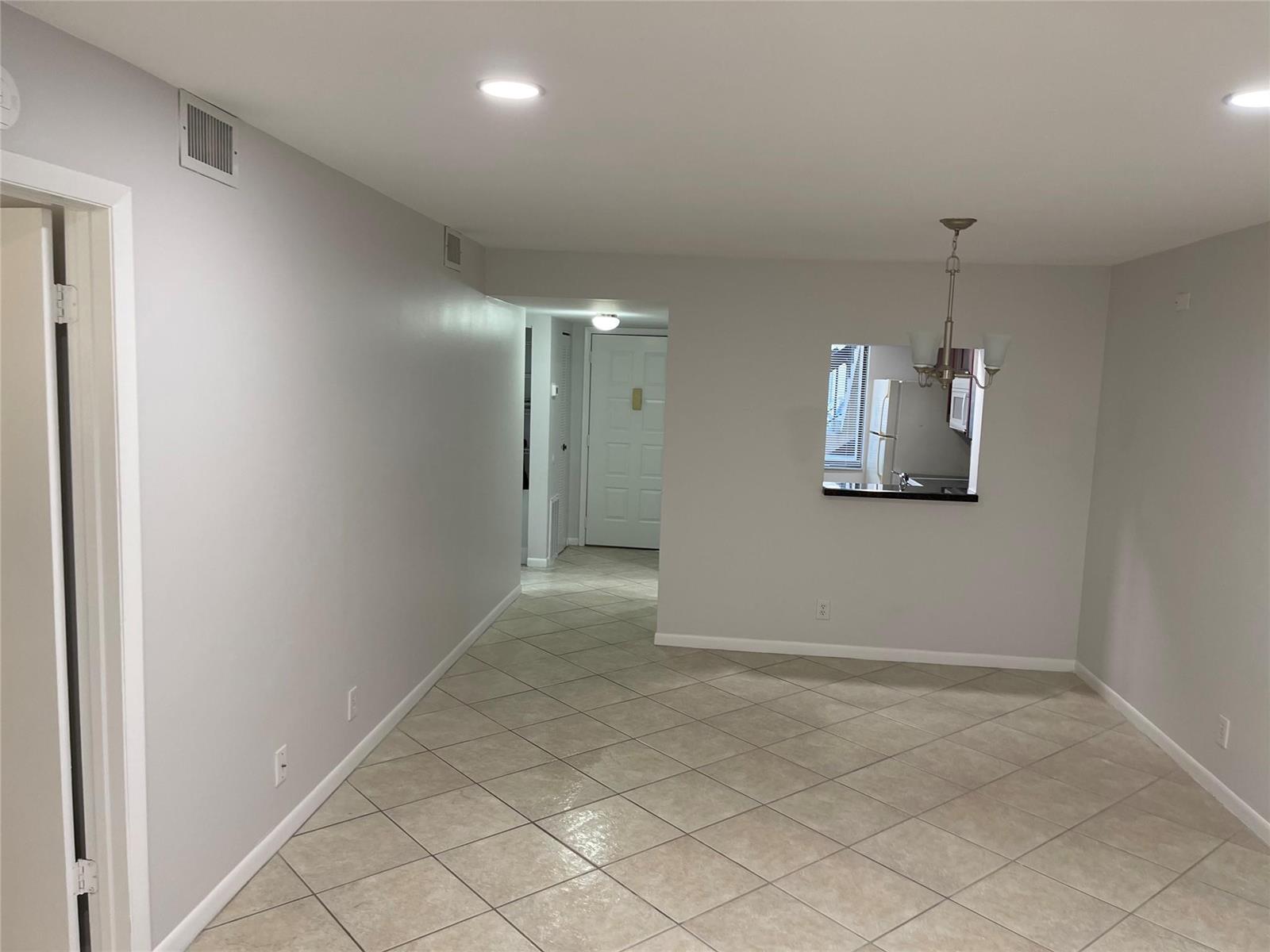An interior view shows a tiled dining area with a pass-through window to the kitchen — 6549 Somerset Drive # 106, Boca Raton FL 33433, BOCA RATON, FL