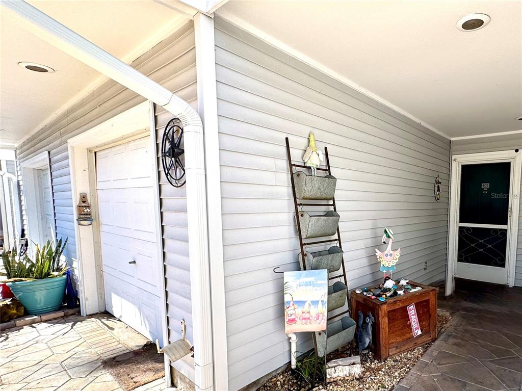A covered porch features light gray siding, a white door, and decorative metal wall planters — 2111 VISTA DEL SOL CIRCLE UNIT 403, LUTZ, FL