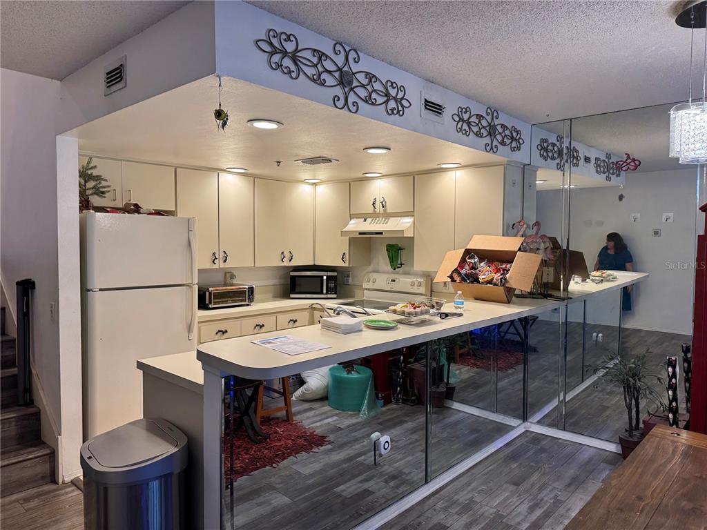 A kitchen features white cabinetry, a breakfast bar, and a mirrored wall backsplash — 2111 VISTA DEL SOL CIRCLE UNIT 403, LUTZ, FL