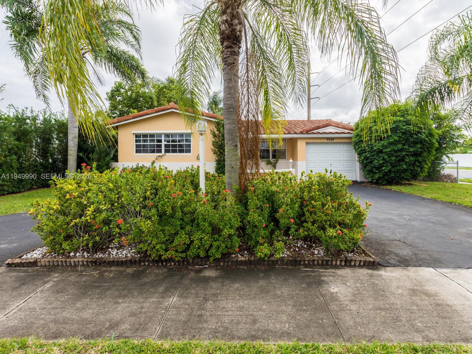 A single-story house with a tan exterior, tile roof, and a large front garden — 5524 Garfield St, Hollywood FL 33021, HOLLYWOOD, FL