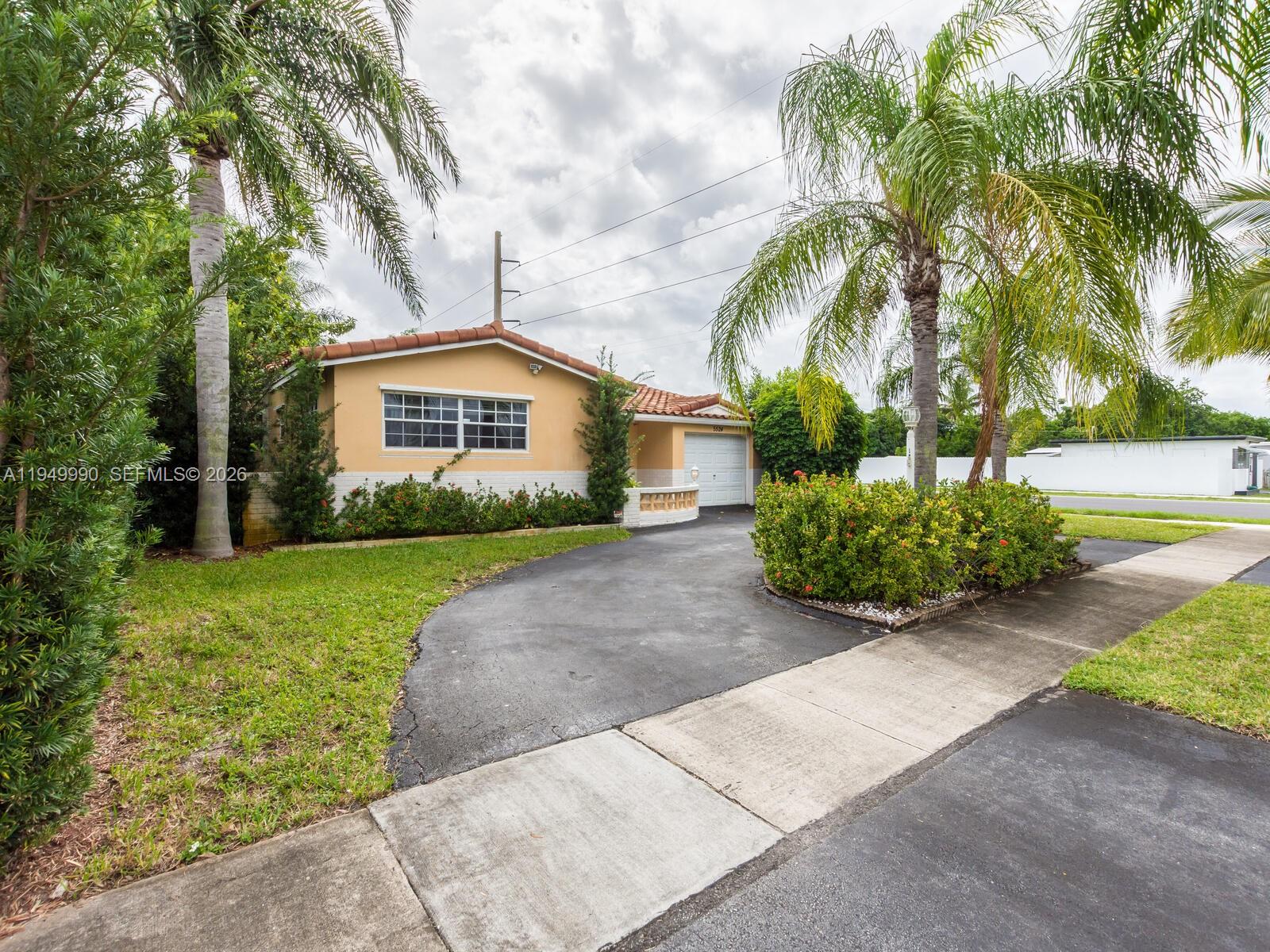 A single-story house with a tan exterior, tile roof, and a paved driveway — 5524 Garfield St, Hollywood FL 33021, HOLLYWOOD, FL