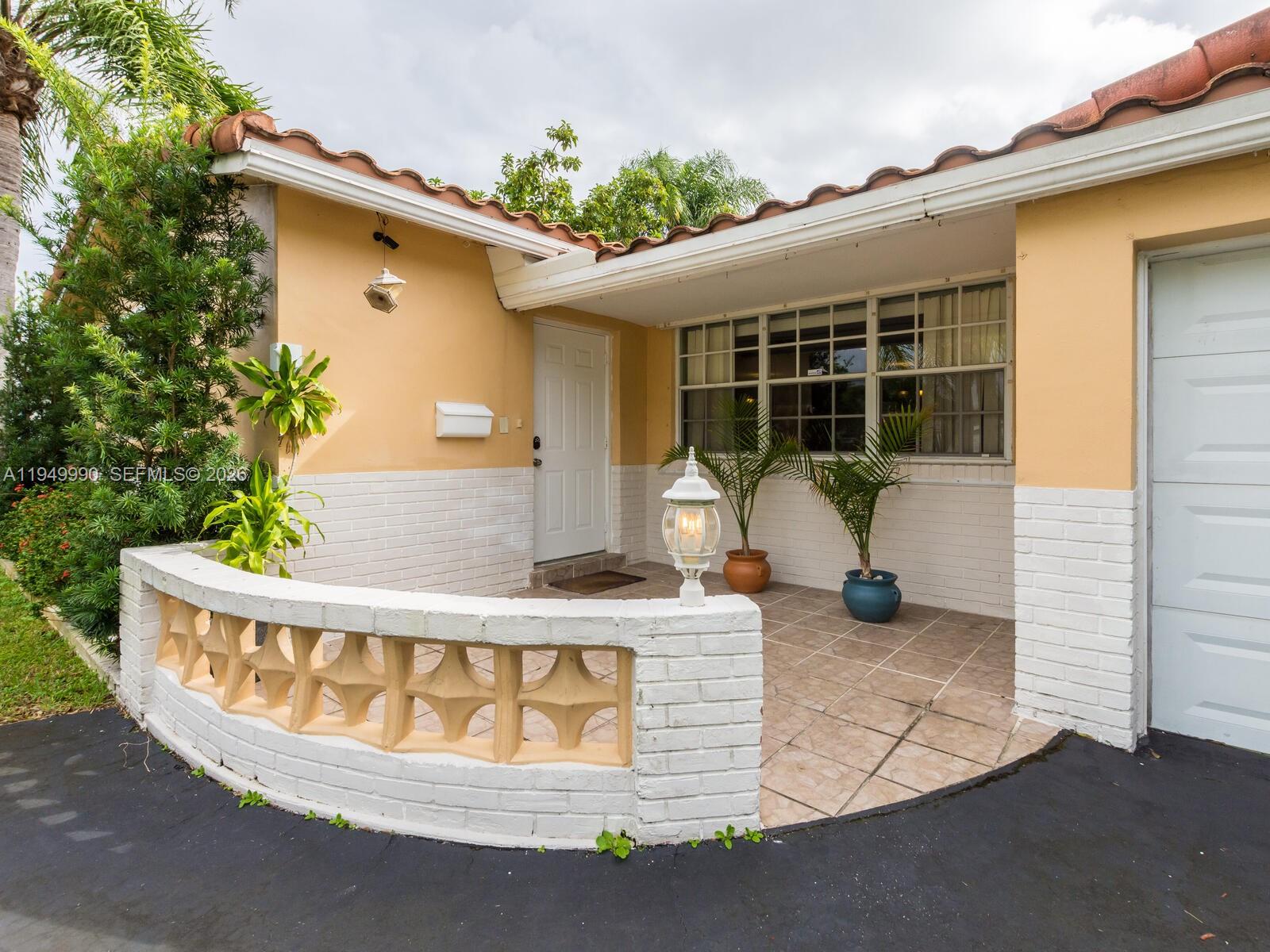 A tan house exterior features a white brick wall, a tiled patio, and a front door — 5524 Garfield St, Hollywood FL 33021, HOLLYWOOD, FL