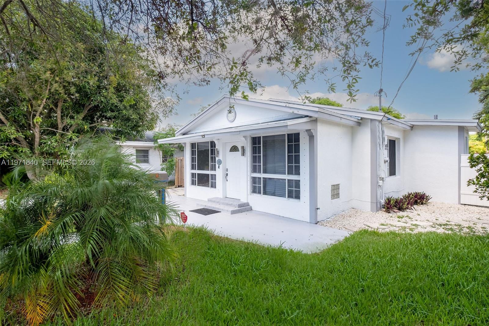 A white single-story house features a front porch, large windows, and a grassy yard — 132 SW 2nd Ave, Hallandale Beach FL 33009, HALLANDALE BEACH, FL