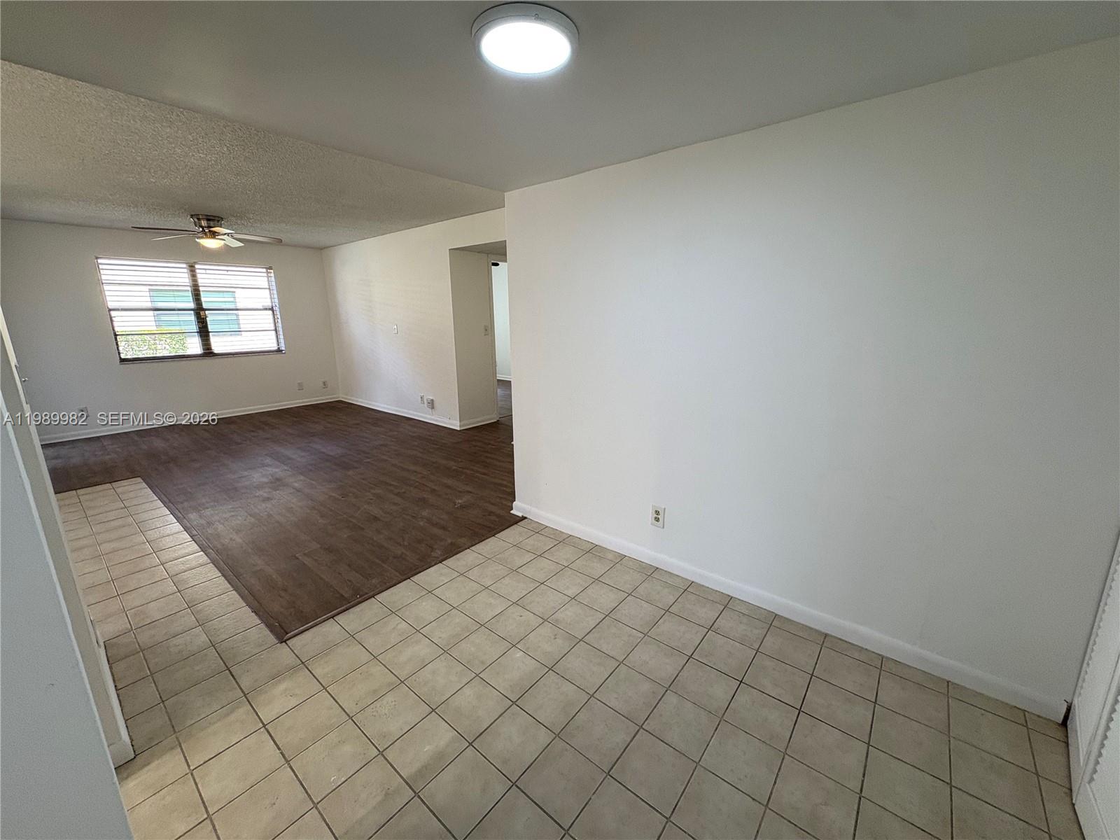 A room with tiled flooring transitions into a living area featuring dark wood-look flooring — 8444 Shadow Ct # 3, Coral Springs FL 33071, CORAL SPRINGS, FL