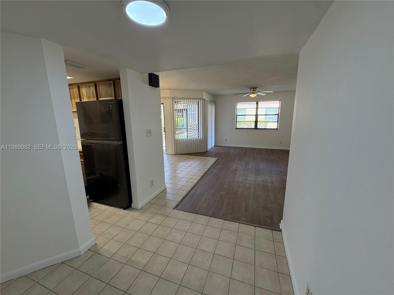 A view from a tiled kitchen area looking into a living room with wood flooring — 8444 Shadow Ct # 3, Coral Springs FL 33071, CORAL SPRINGS, FL