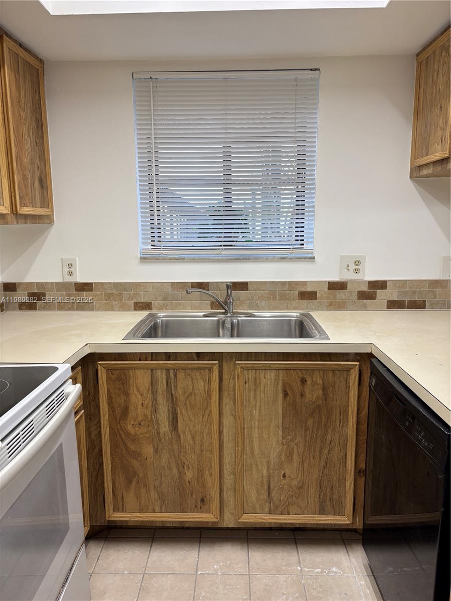 A kitchen features wood cabinets, a stainless steel sink, and a tiled backsplash — 8444 Shadow Ct # 3, Coral Springs FL 33071, CORAL SPRINGS, FL