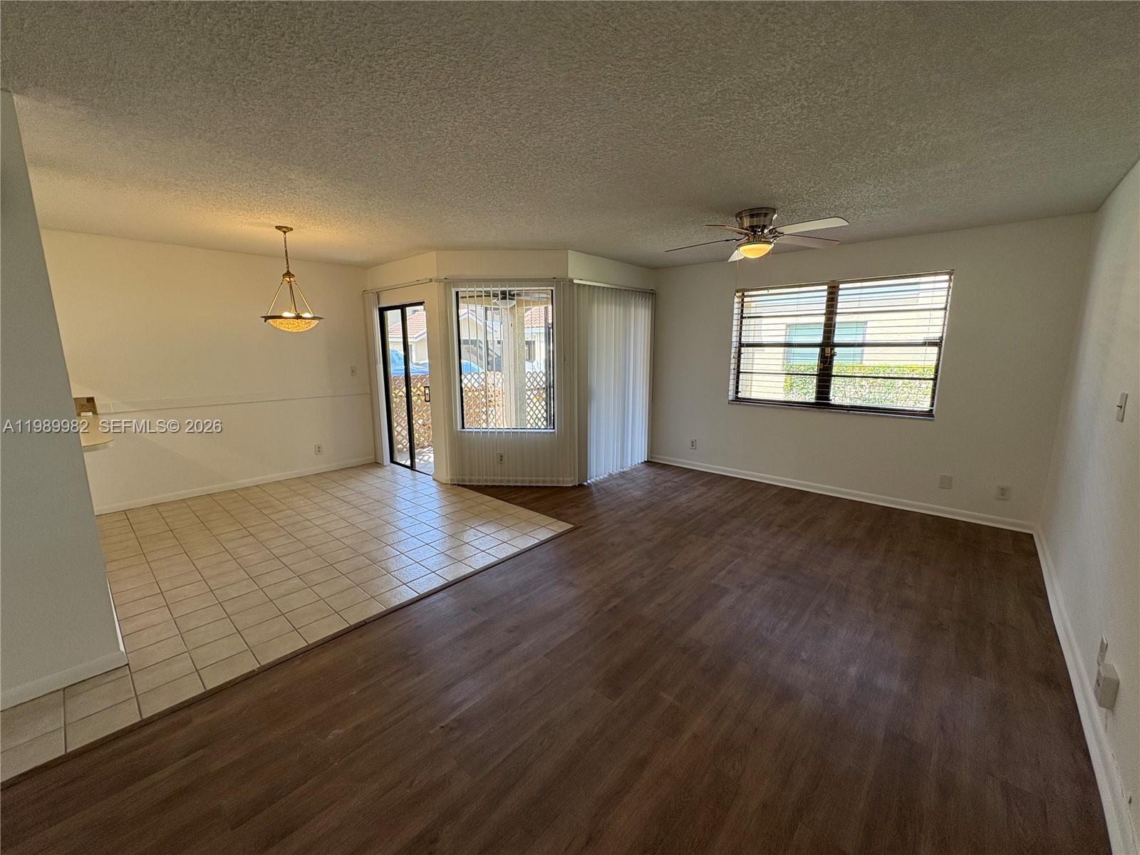An open-concept living and dining area features tile flooring, wood-look laminate, and a sliding door — 8444 Shadow Ct # 3, Coral Springs FL 33071, CORAL SPRINGS, FL