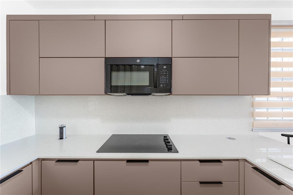 A modern kitchen features taupe flat-panel cabinets, a black microwave, and a white countertop — SR 307 km 7.4 COND PASEO DEL MAR BOQUERON WARD UNIT 104, BOQUERON, PR