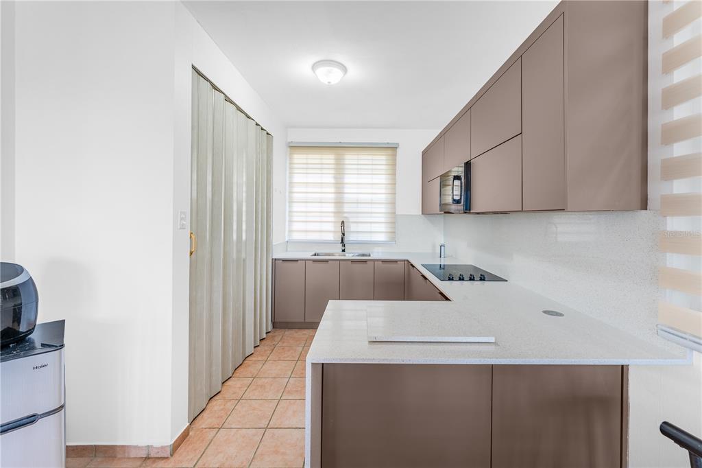 A kitchen features brown flat-panel cabinets, white countertops, and a light-colored folding door — SR 307 km 7.4 COND PASEO DEL MAR BOQUERON WARD UNIT 104, BOQUERON, PR