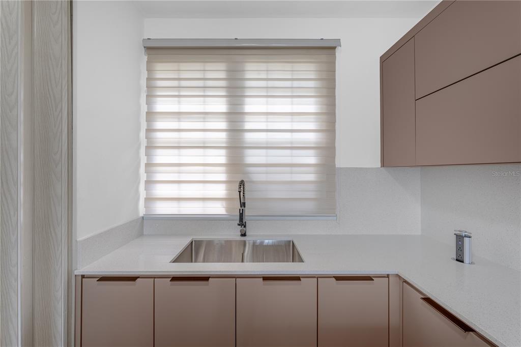 A modern kitchen features light-colored countertops, a stainless steel sink, and muted brown cabinetry — SR 307 km 7.4 COND PASEO DEL MAR BOQUERON WARD UNIT 104, BOQUERON, PR