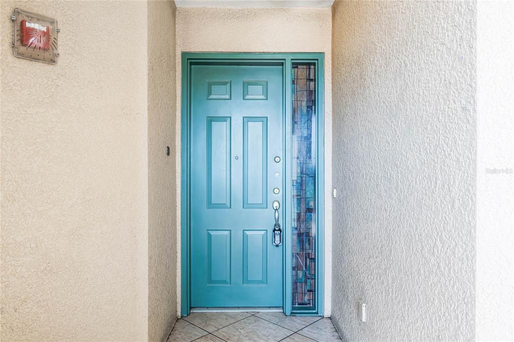 A teal front door with a stained glass sidelight is set in a stucco entryway — 8761 THE ESPLANADE UNIT 22, ORLANDO, FL