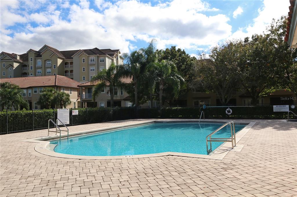 A rectangular swimming pool is surrounded by a paved deck and residential apartment buildings — 8761 THE ESPLANADE UNIT 22, ORLANDO, FL