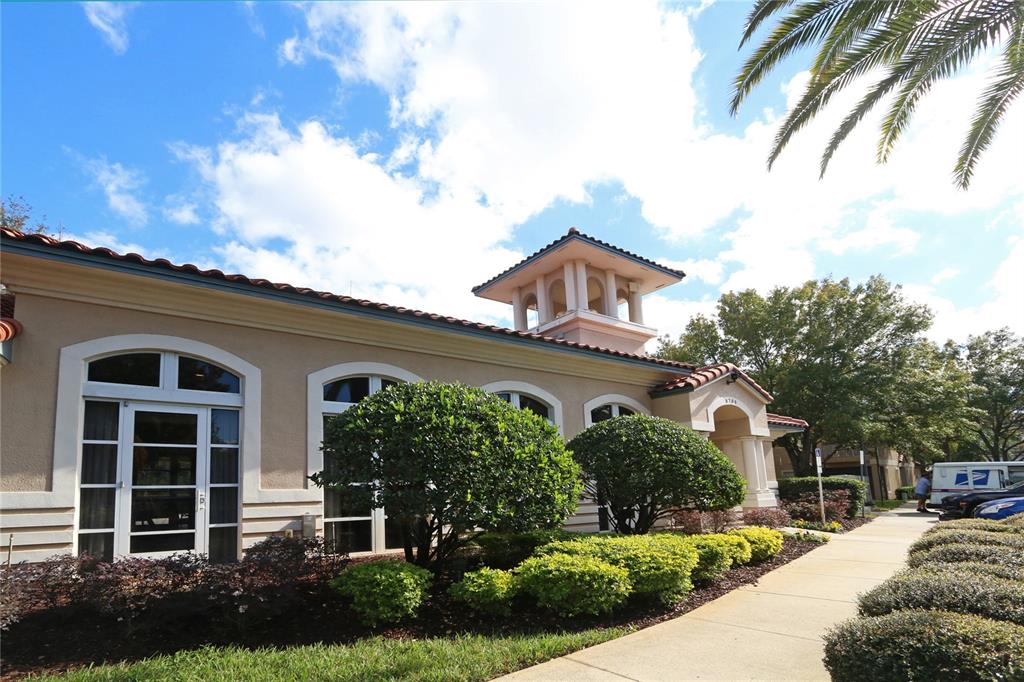 A tan building with a tile roof, arched windows, and a cupola under a blue sky — 8761 THE ESPLANADE UNIT 22, ORLANDO, FL