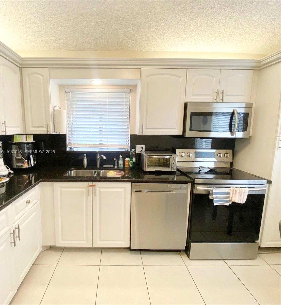 A kitchen features white cabinets, stainless steel appliances, and dark countertops — 8089 Sweetbriar Way, Boca Raton FL 33496, BOCA RATON, FL