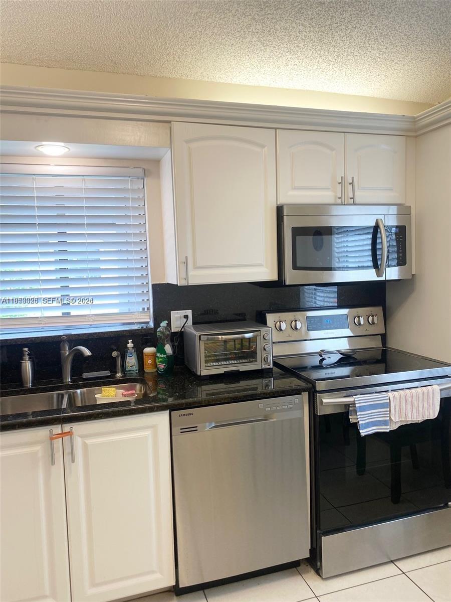 A kitchen features white cabinets, stainless steel appliances, and black granite countertops — 8089 Sweetbriar Way, Boca Raton FL 33496, BOCA RATON, FL
