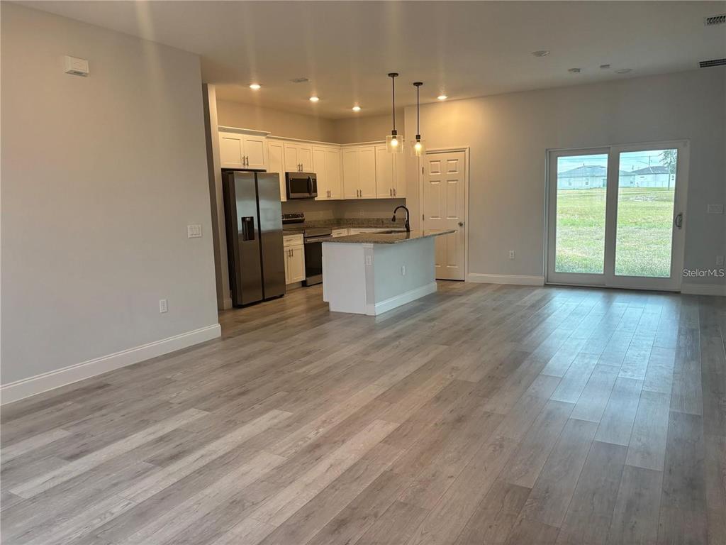 A kitchen with white cabinets and stainless steel appliances opens to a spacious living area — 423 CHURCHILL COURT, KISSIMMEE, FL