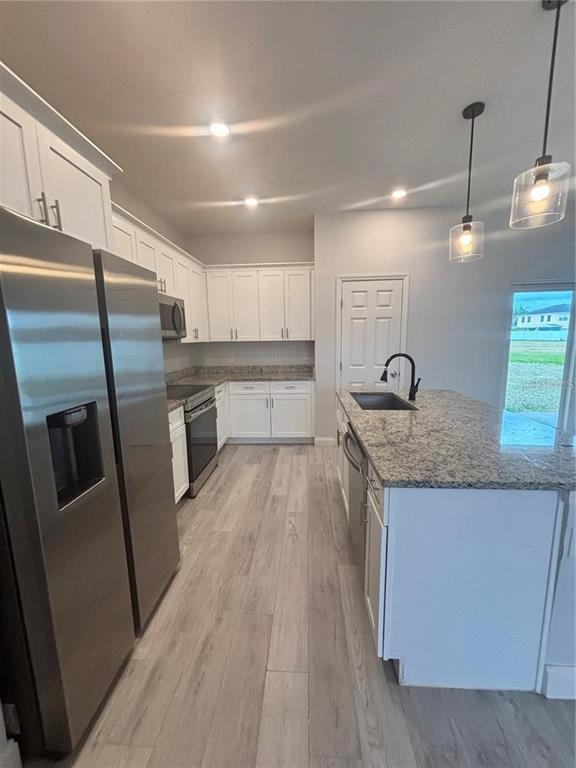 A kitchen features white cabinets, granite countertops, stainless steel appliances, and a central island — 423 CHURCHILL COURT, KISSIMMEE, FL