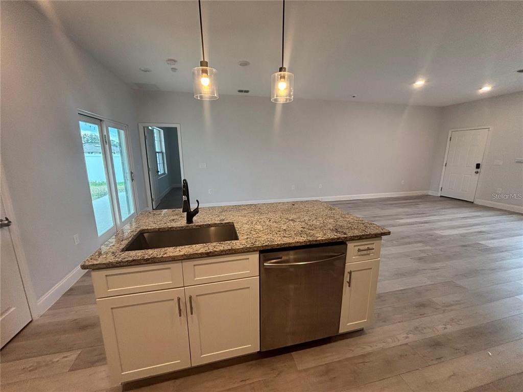 A kitchen island with a stainless steel sink and dishwasher sits in an open room — 423 CHURCHILL COURT, KISSIMMEE, FL