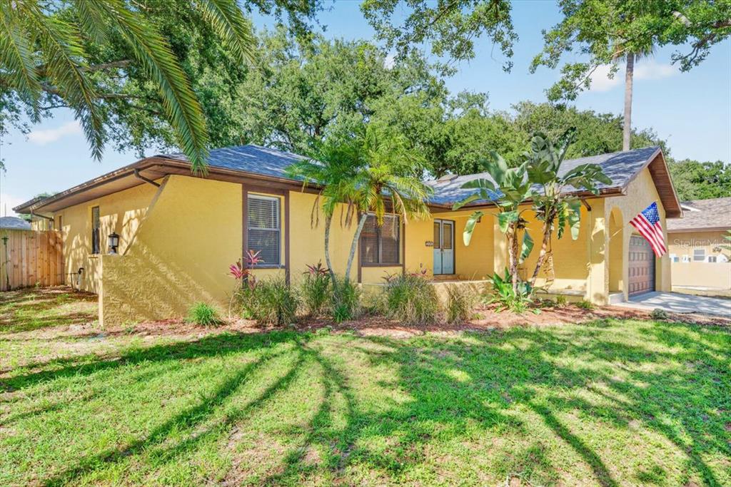A yellow single-story house with a front porch, palm trees, and an American flag — 2883 MANDARIN PLACE, PALM HARBOR, FL