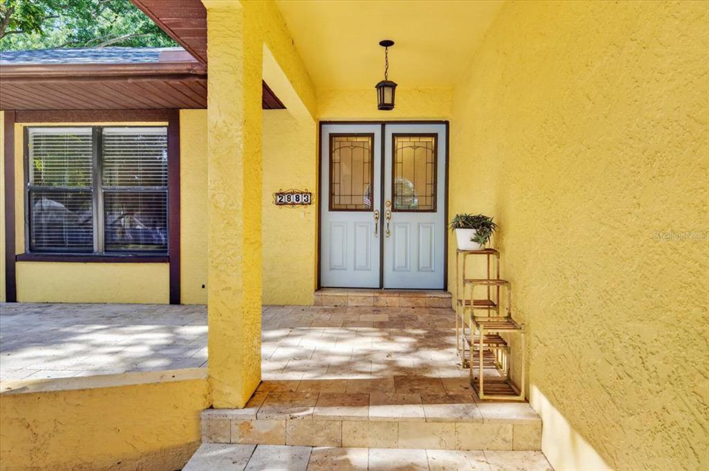 A yellow exterior wall features a double front door with glass panels and stone steps — 2883 MANDARIN PLACE, PALM HARBOR, FL