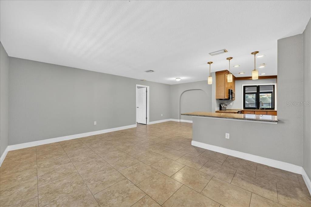 An open-concept living area features light gray walls, tile flooring, and a kitchen breakfast bar — 2883 MANDARIN PLACE, PALM HARBOR, FL
