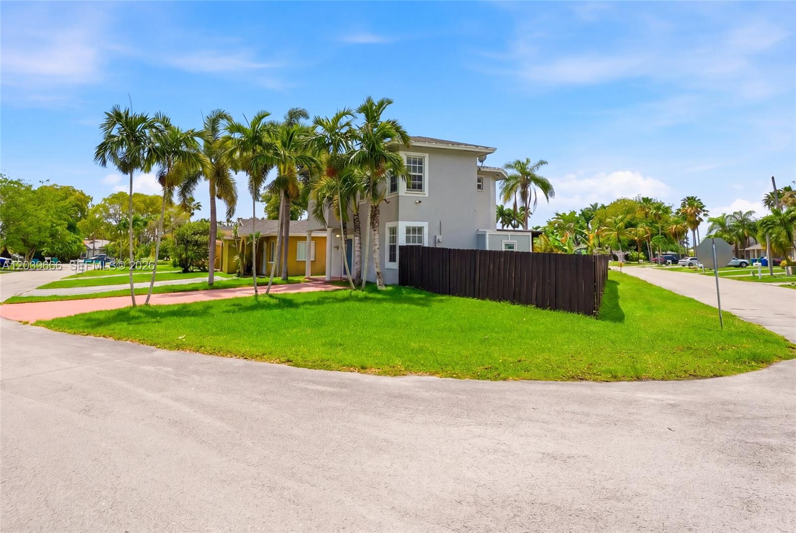 A two-story gray house with a wooden fence stands on a corner lot with palms — FLORIDA CITY, FL