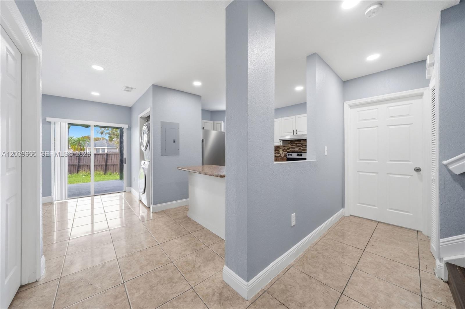 A light blue kitchen and dining area features tile flooring, a breakfast bar, and laundry — FLORIDA CITY, FL