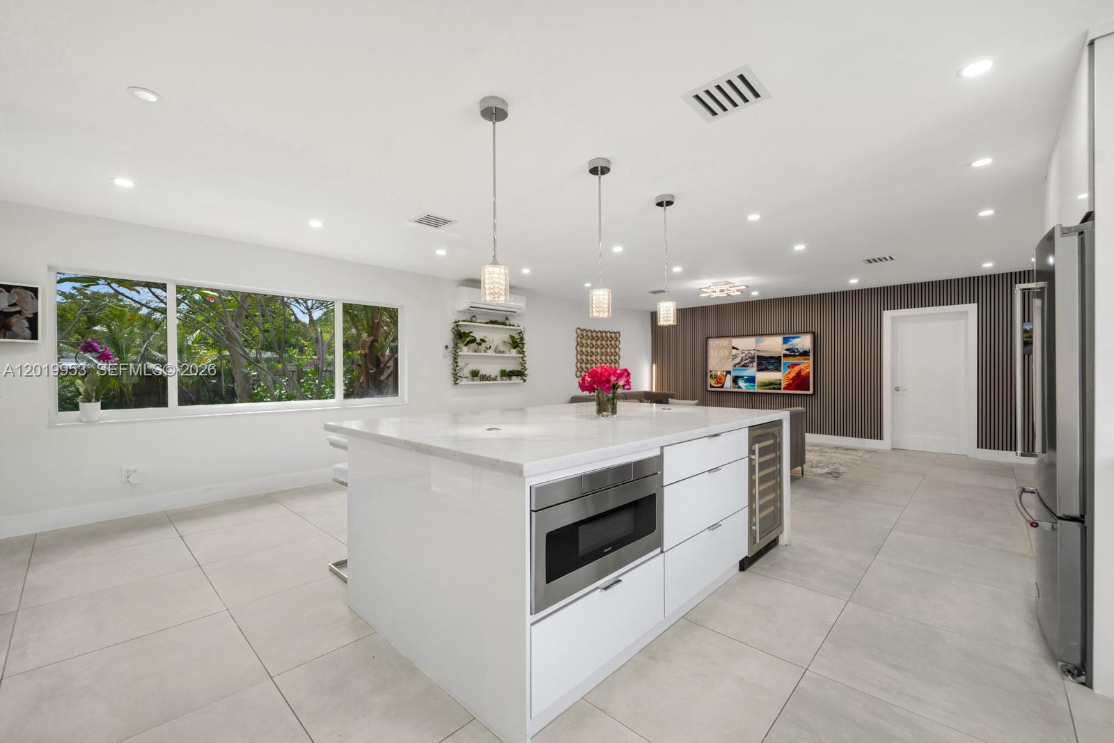A modern white kitchen features a large center island with a built-in microwave and refrigerator — 600 NE 4th St, Pompano Beach FL 33060, POMPANO BEACH, FL