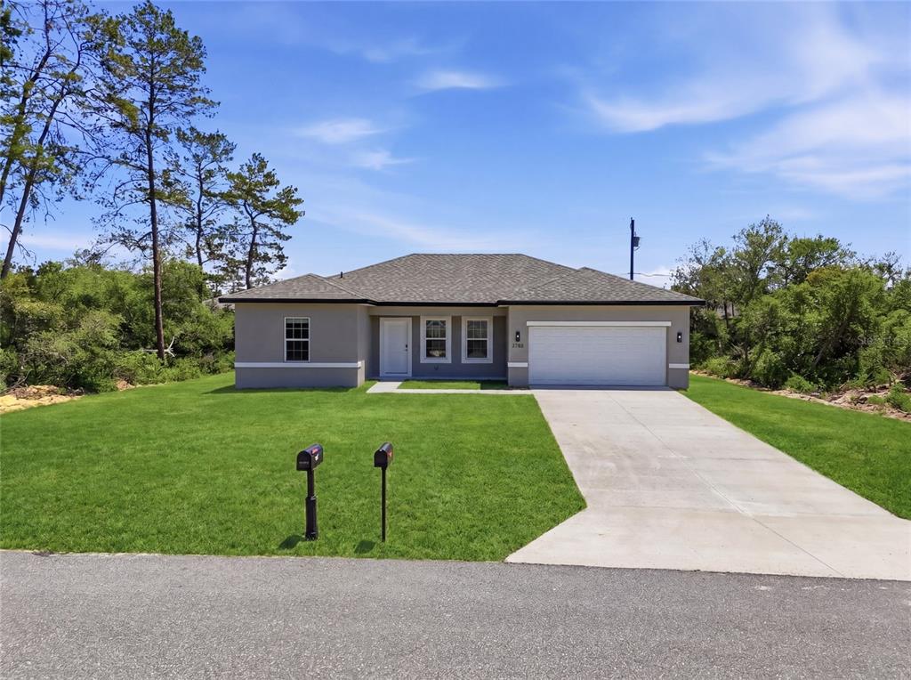 A single-story house with a gray stucco exterior, white trim, and a two-car garage — 2780 SW 162ND LANE, OCALA, FL